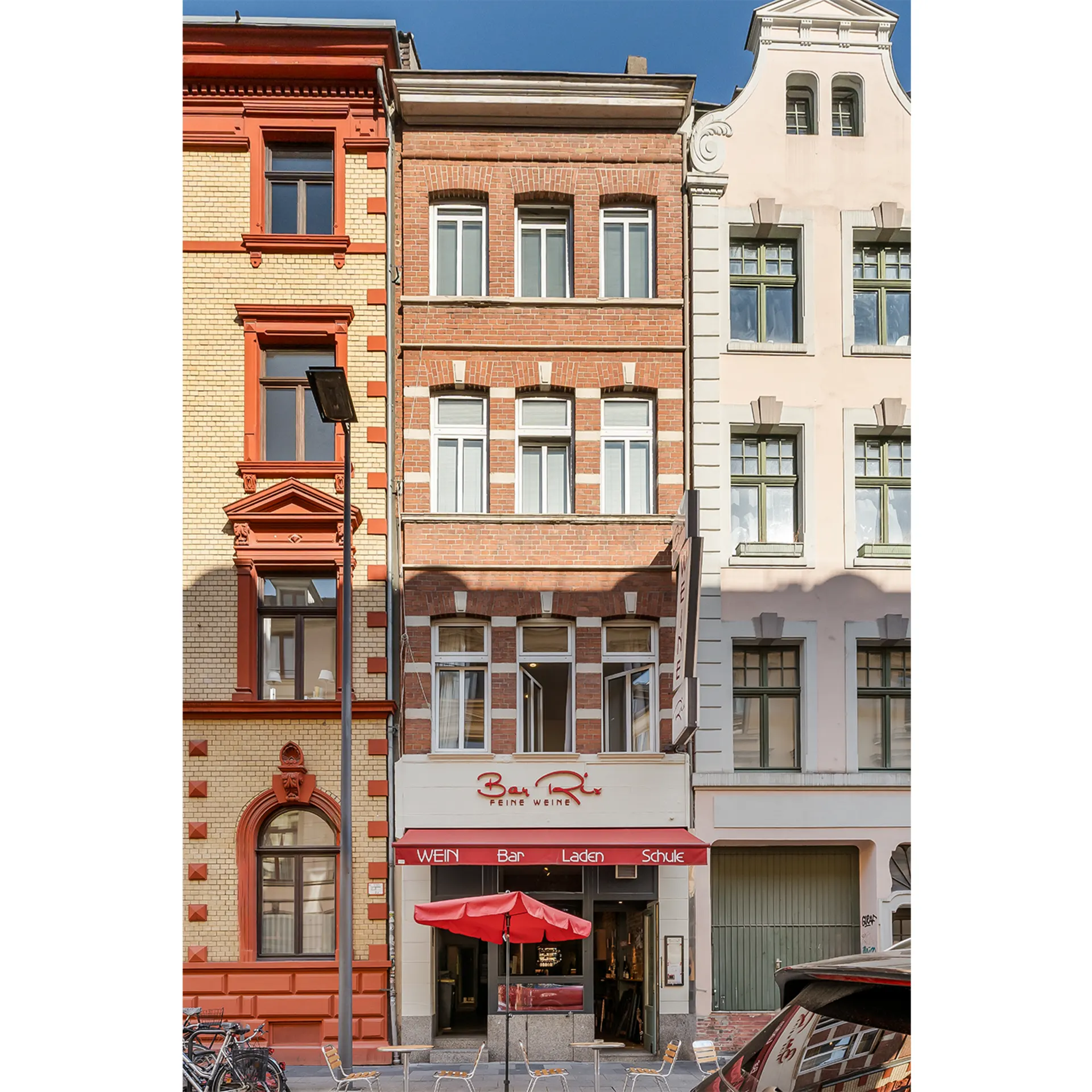 Wohnhaus mit Backsteinfassade, mehreren Fenstern und einem Geschäft im Erdgeschoss.