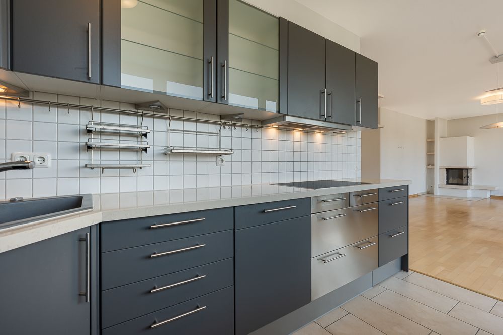 Moderne Einbauküche mit dunklen Schränken, Glastüren und weißem Fliesenspiegel.