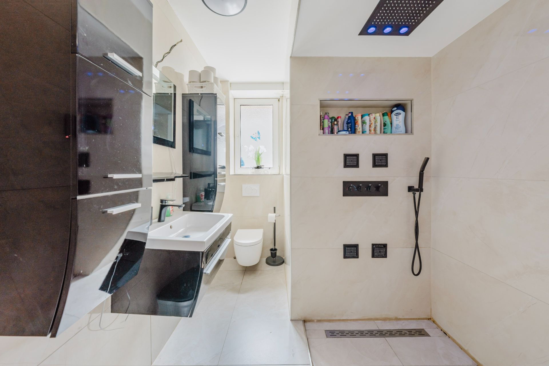 Modernes Badezimmer mit Waschbecken, Toilette und offener Dusche mit Regendusche.