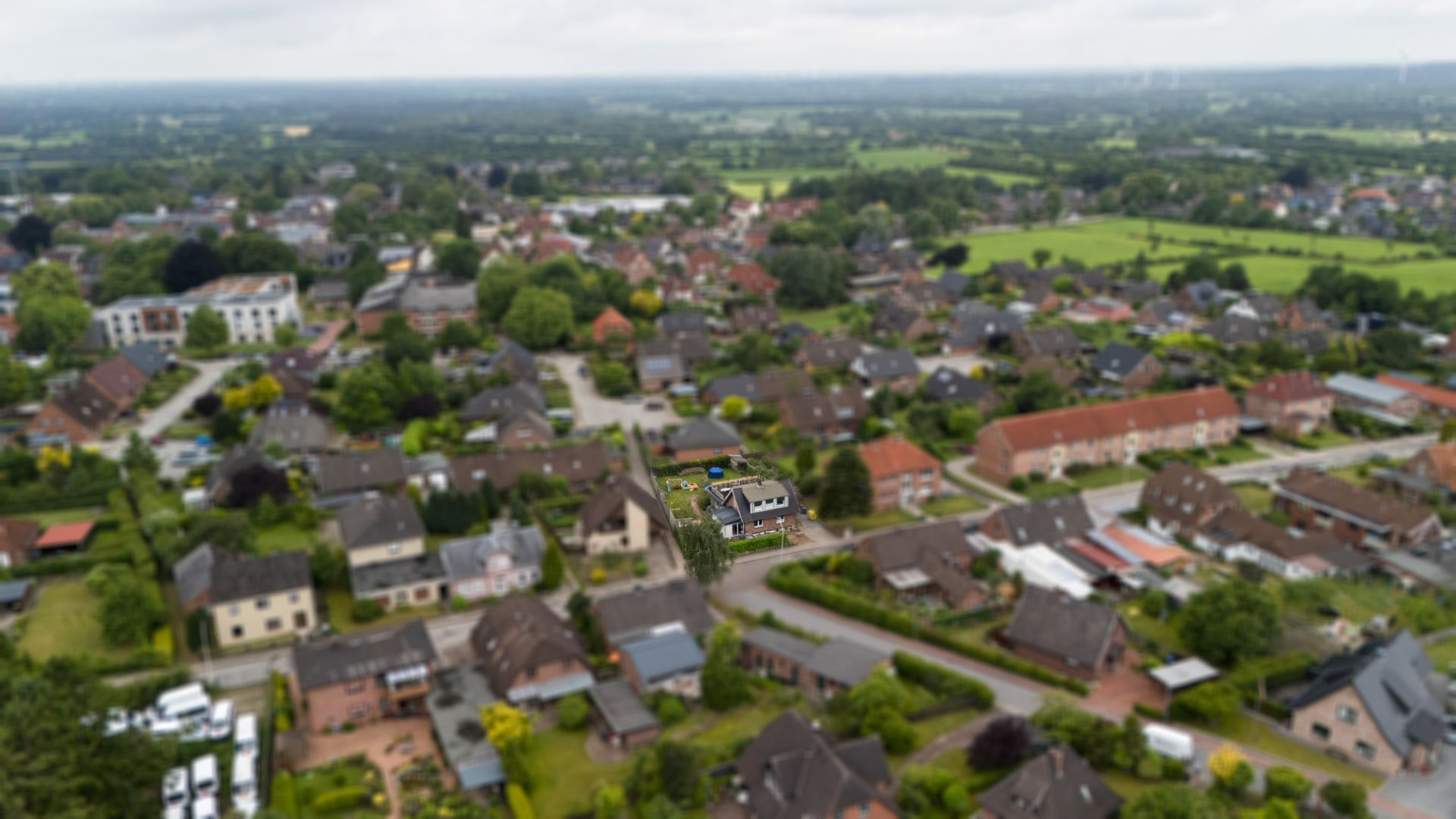 Luftaufnahme eines Wohngebiets mit vielen Häusern und viel Grün.