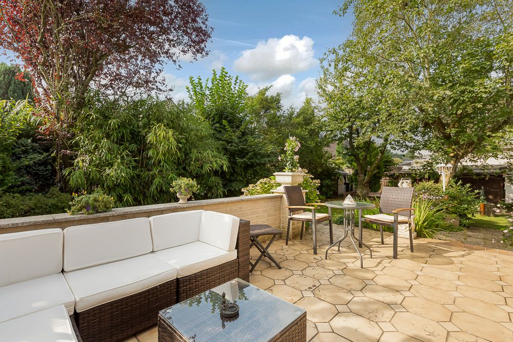 Möblierte Terrasse mit Sitzgruppe, kleinem Tisch und Blick auf den grünen Garten.