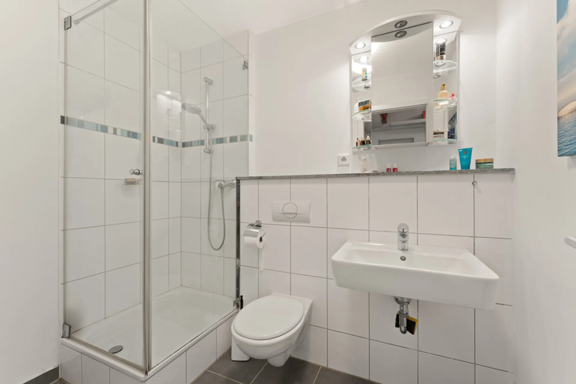 Modernes Badezimmer mit Dusche, Toilette, Waschbecken und beleuchtetem Spiegel.