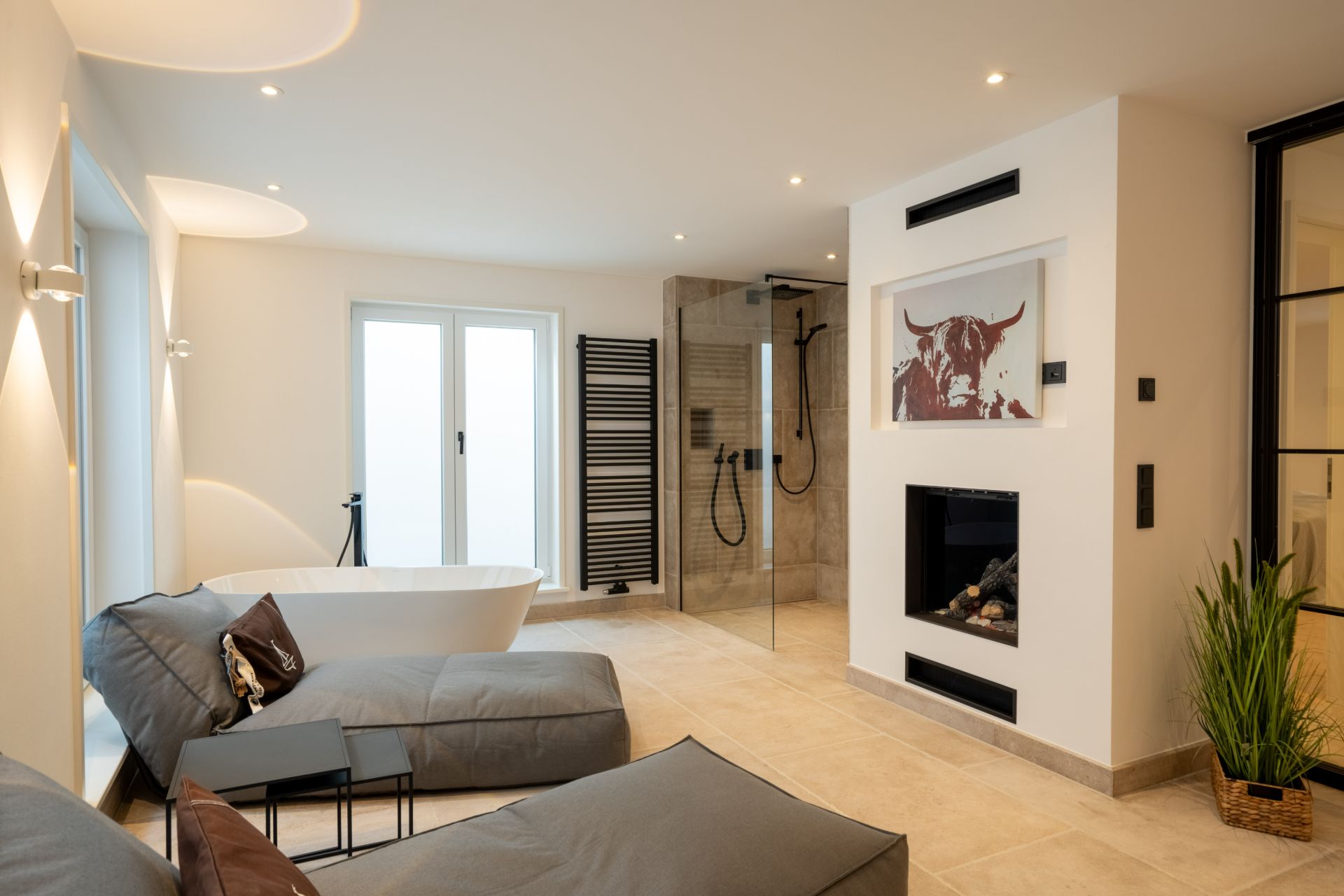 Modernes Badezimmer mit freistehender Badewanne, Dusche, zwei Liegen und Pflanze.