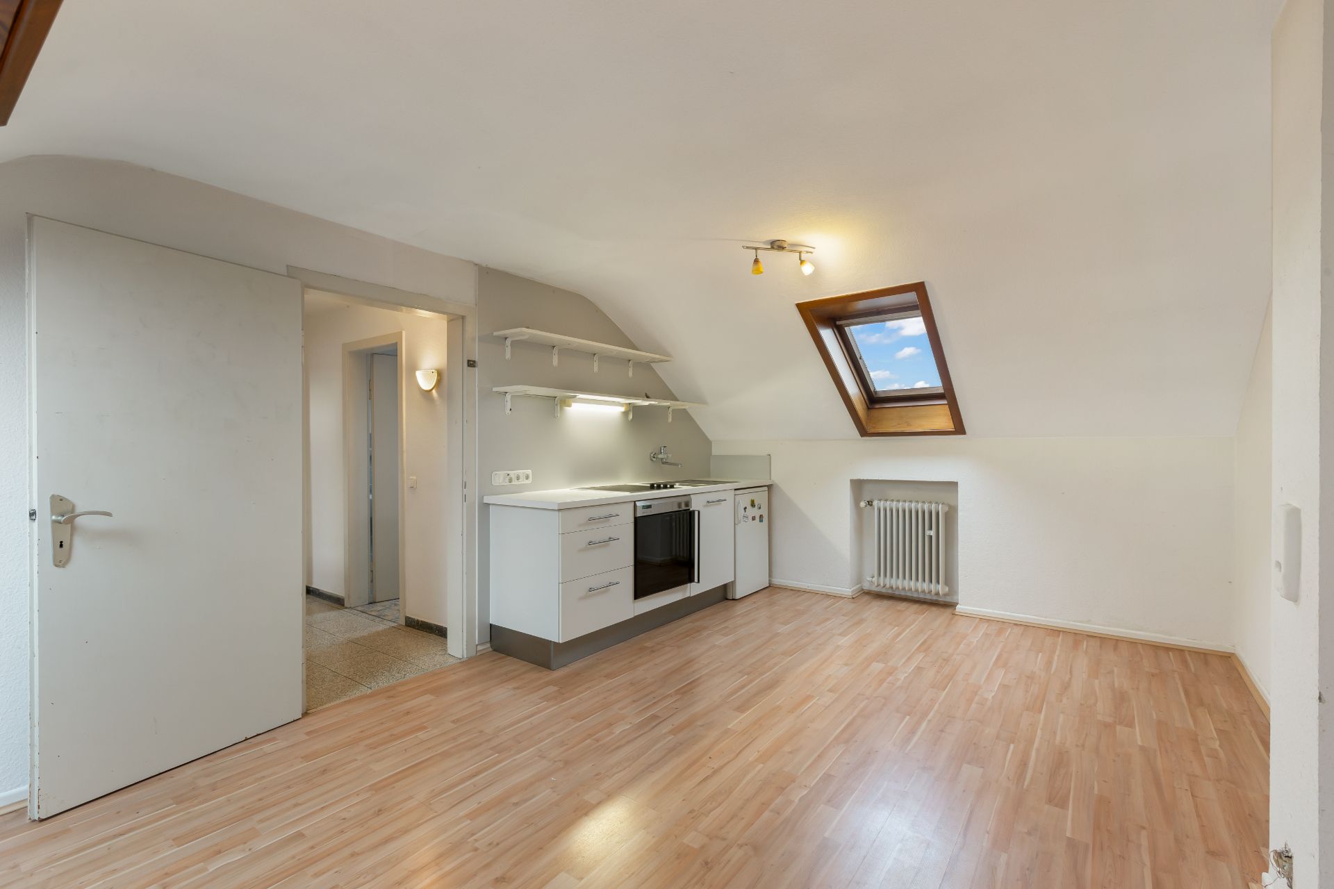 Helle Dachgeschosswohnung mit Einbauküche, Holzfußboden und Dachfenster.