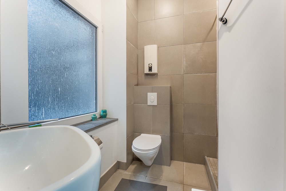 Modernes Bad mit Hänge-WC, Waschbecken und Milchglasfenster.