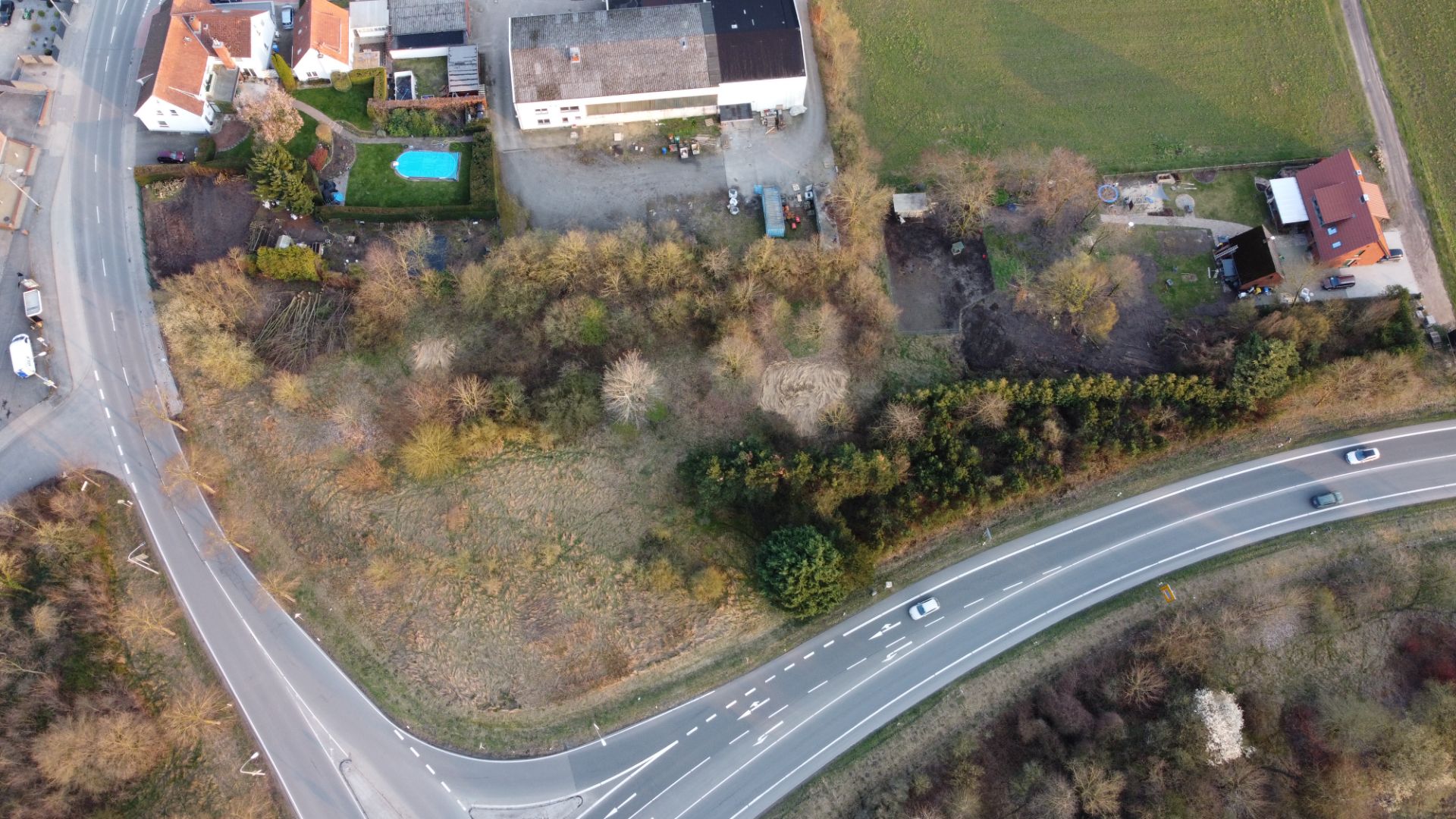 Luftaufnahme von Häusern, einem Garten mit Pool und einer angrenzenden Straße.
