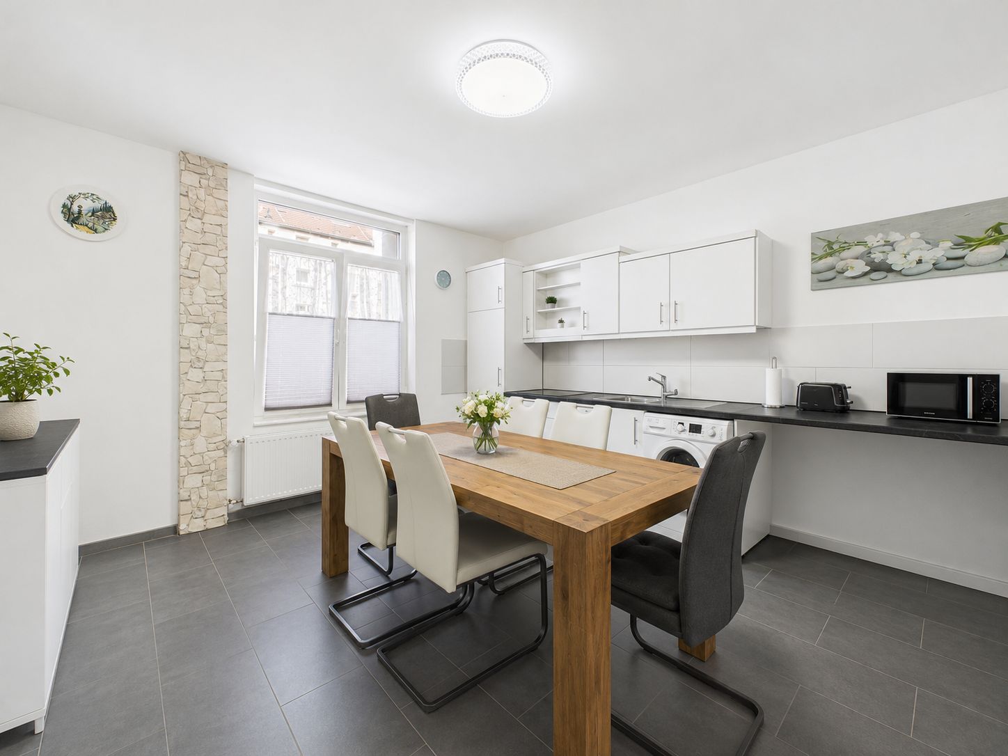 Moderne Küche mit großem Holztisch, sechs Stühlen und weißen Schränken.