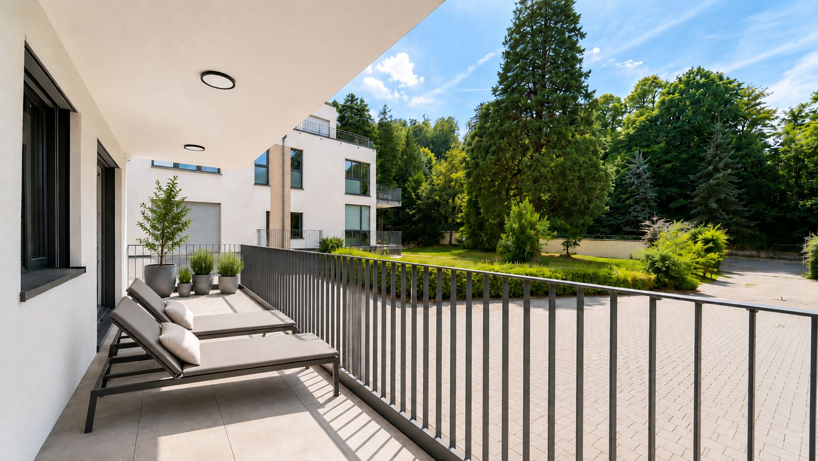 Geräumiger Balkon mit Liegen, Pflanzen und Blick auf Garten und Bäume.