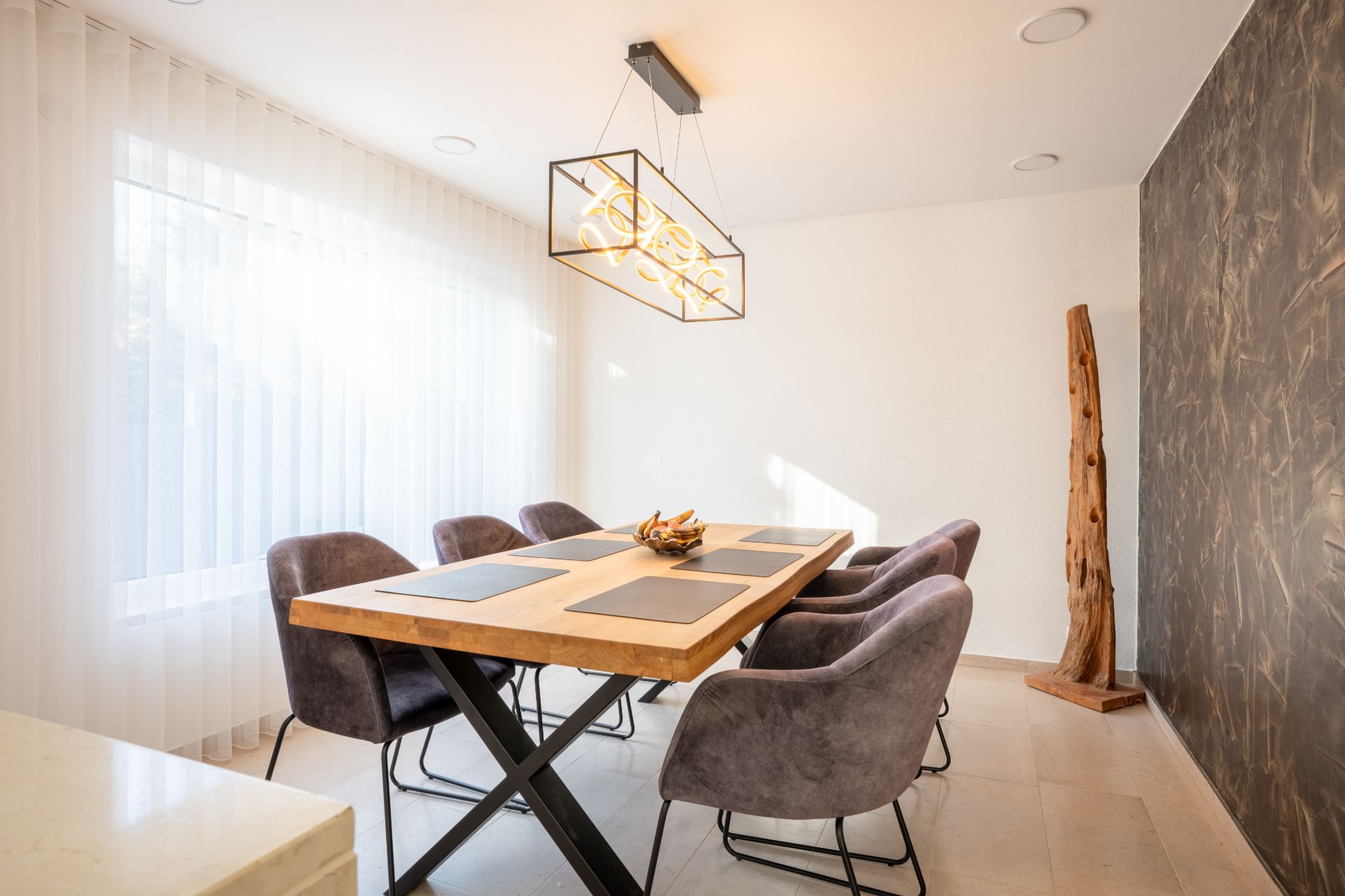 Modernes Esszimmer mit Holztisch, sechs Stühlen und großer Fensterfront mit Vorhang.