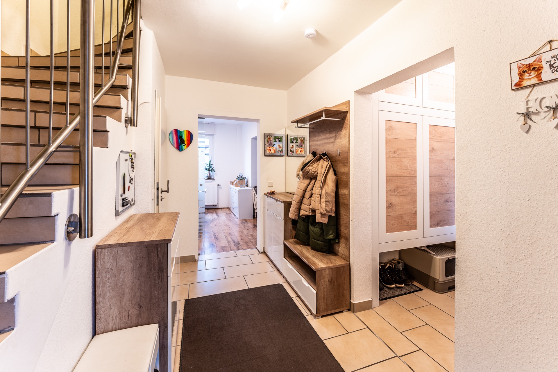 Heller Flur mit Treppe, Garderobe, Schuhablage und Zugang zu weiteren Zimmern.