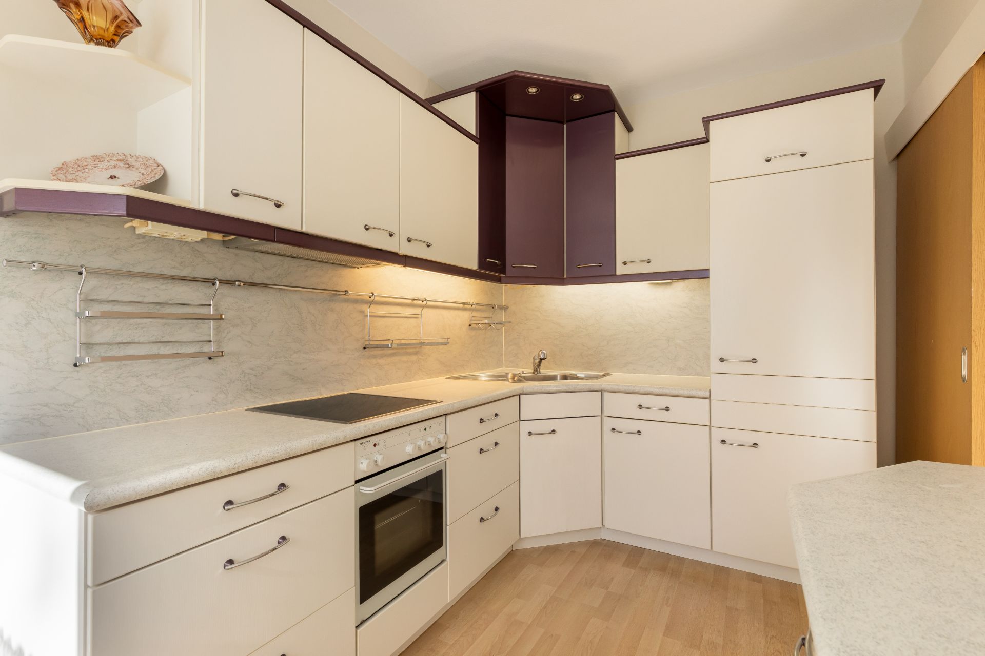 Moderne Einbauküche mit weißen Schränken, Herd, Spüle und Holzfußboden.