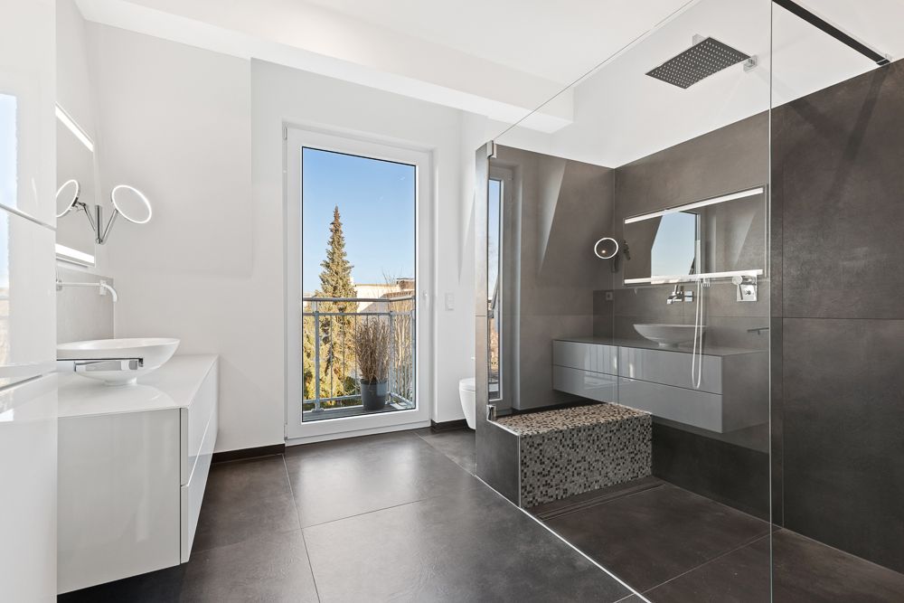 Modernes Badezimmer mit großer Dusche, zwei Waschbecken und Fenster mit Blick nach draußen.