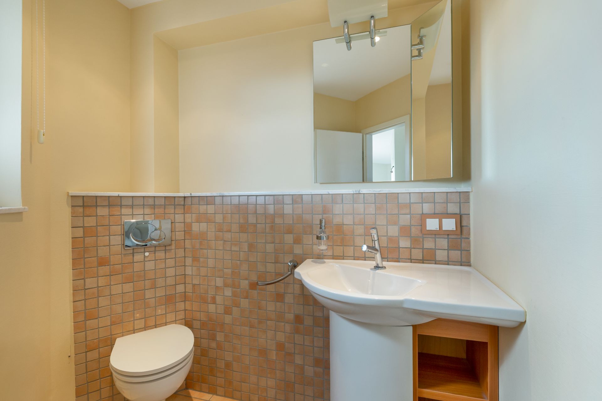 Modernes Badezimmer mit Wand-WC, Waschbecken und großem Spiegel über Fliesenwand.