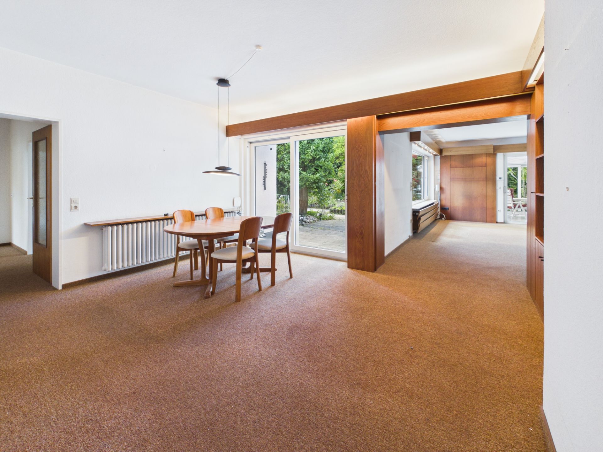 Helles Esszimmer mit Holztisch, vier Stühlen und großem Fenster zum Garten.
