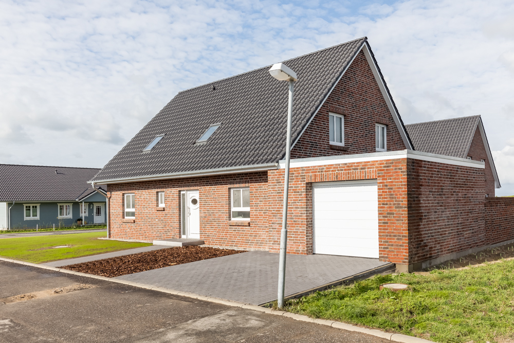Modernes Einfamilienhaus aus rotem Klinker mit Garage und gepflegtem Vorgarten.