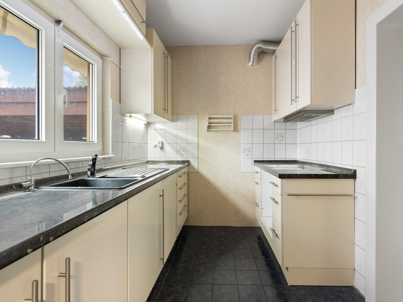 Helle Einbauküche mit schwarzen Arbeitsplatten, Fenster und weißen Fliesen.