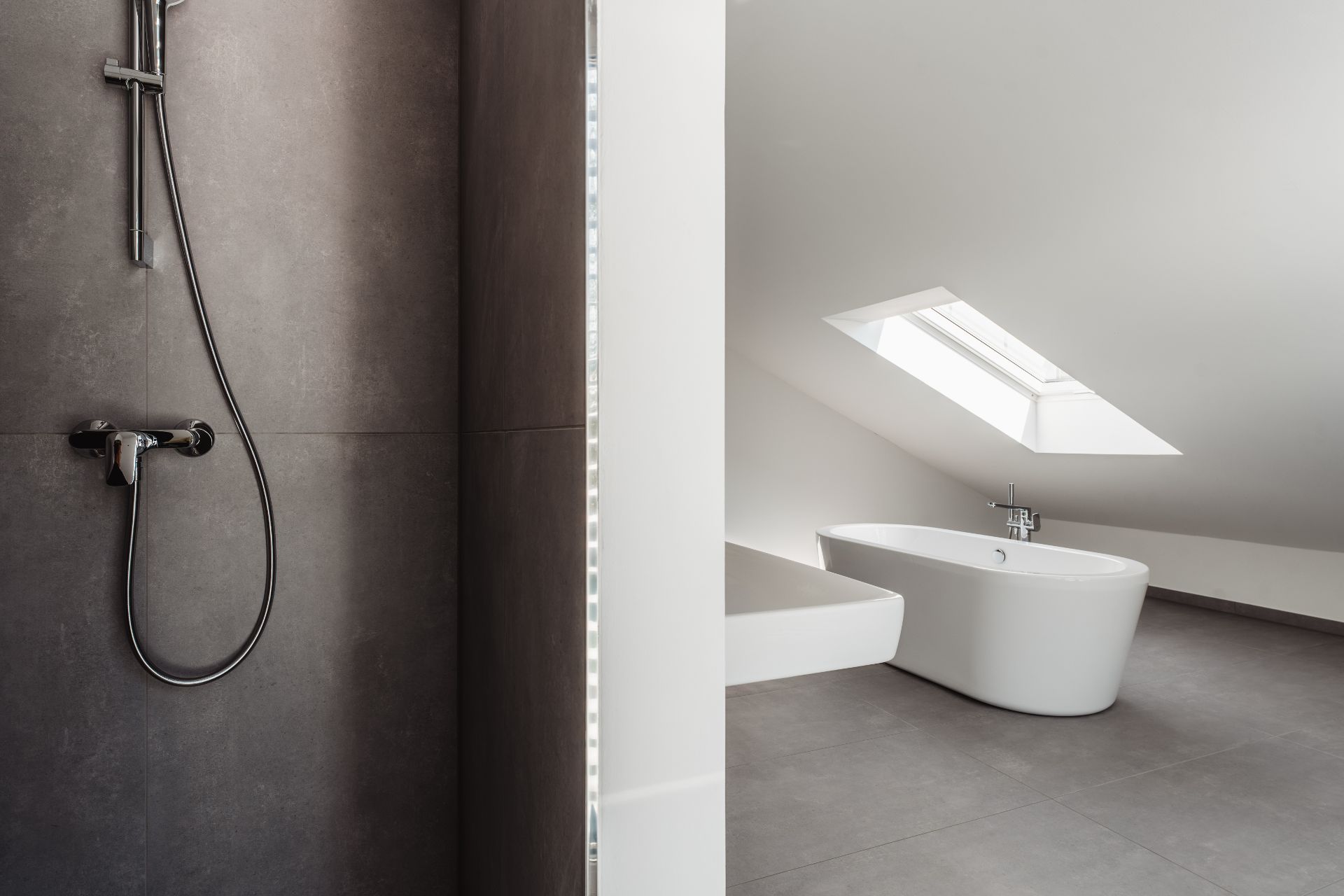 Modernes Bad mit Duscharmatur und freistehender Badewanne unter Dachfenster.