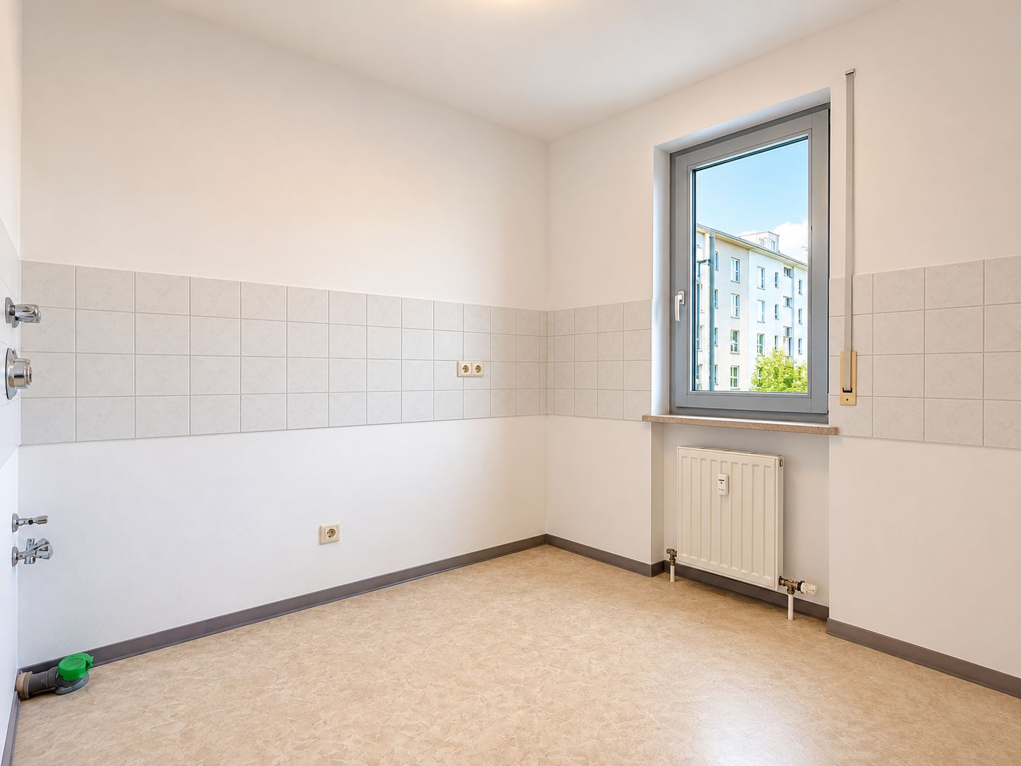 Leerer Raum mit Fliesen an der Wand, Fenster und Heizkörper.