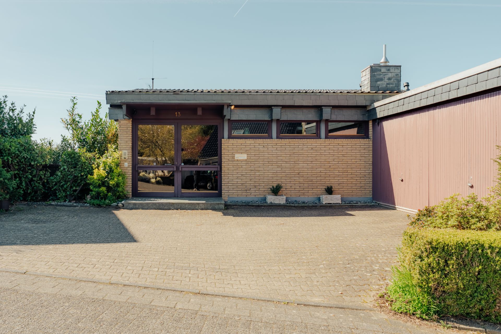 Einfamilienhaus mit Flachdach, Backsteinfassade und großer Einfahrt.