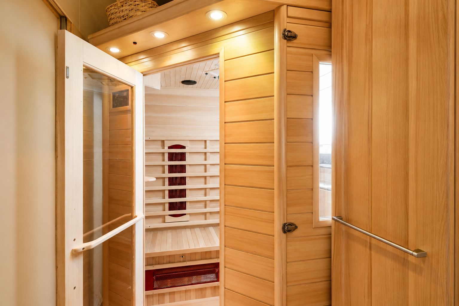 Innenansicht einer modernen Holzsauna mit Glastür und Beleuchtung.