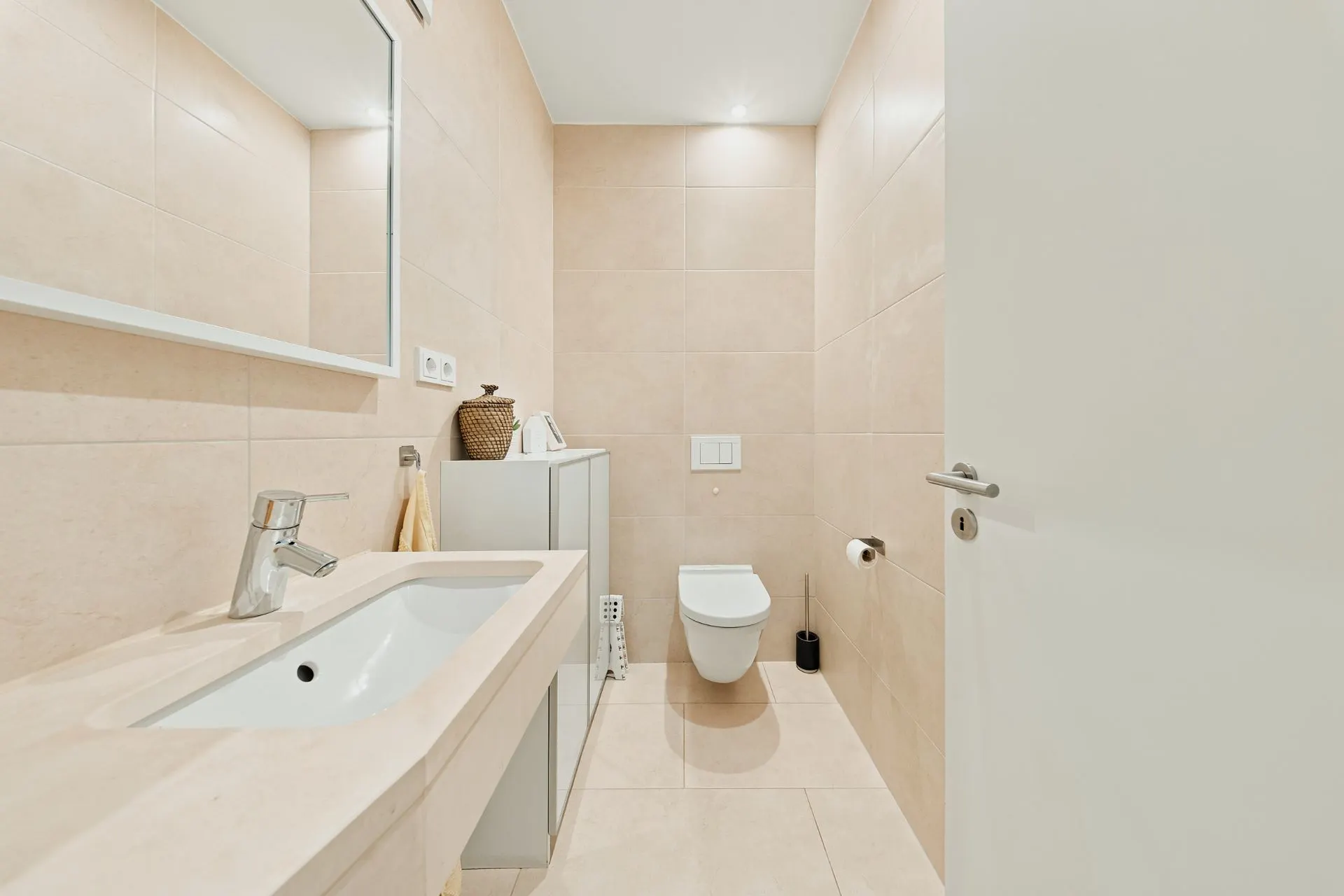 Modernes, helles Badezimmer mit Waschbecken, Spiegel und Wandtoilette.
