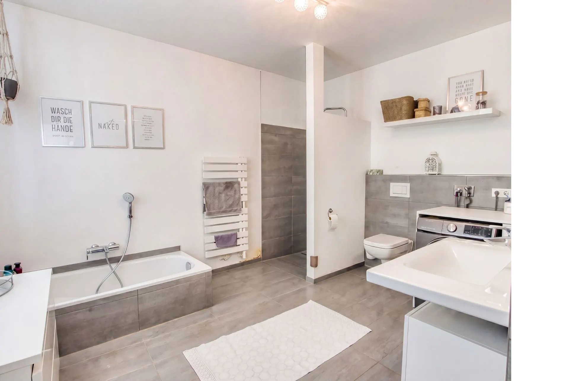 Modernes Badezimmer mit Badewanne, Dusche, Waschbecken, Toilette und Waschmaschine.