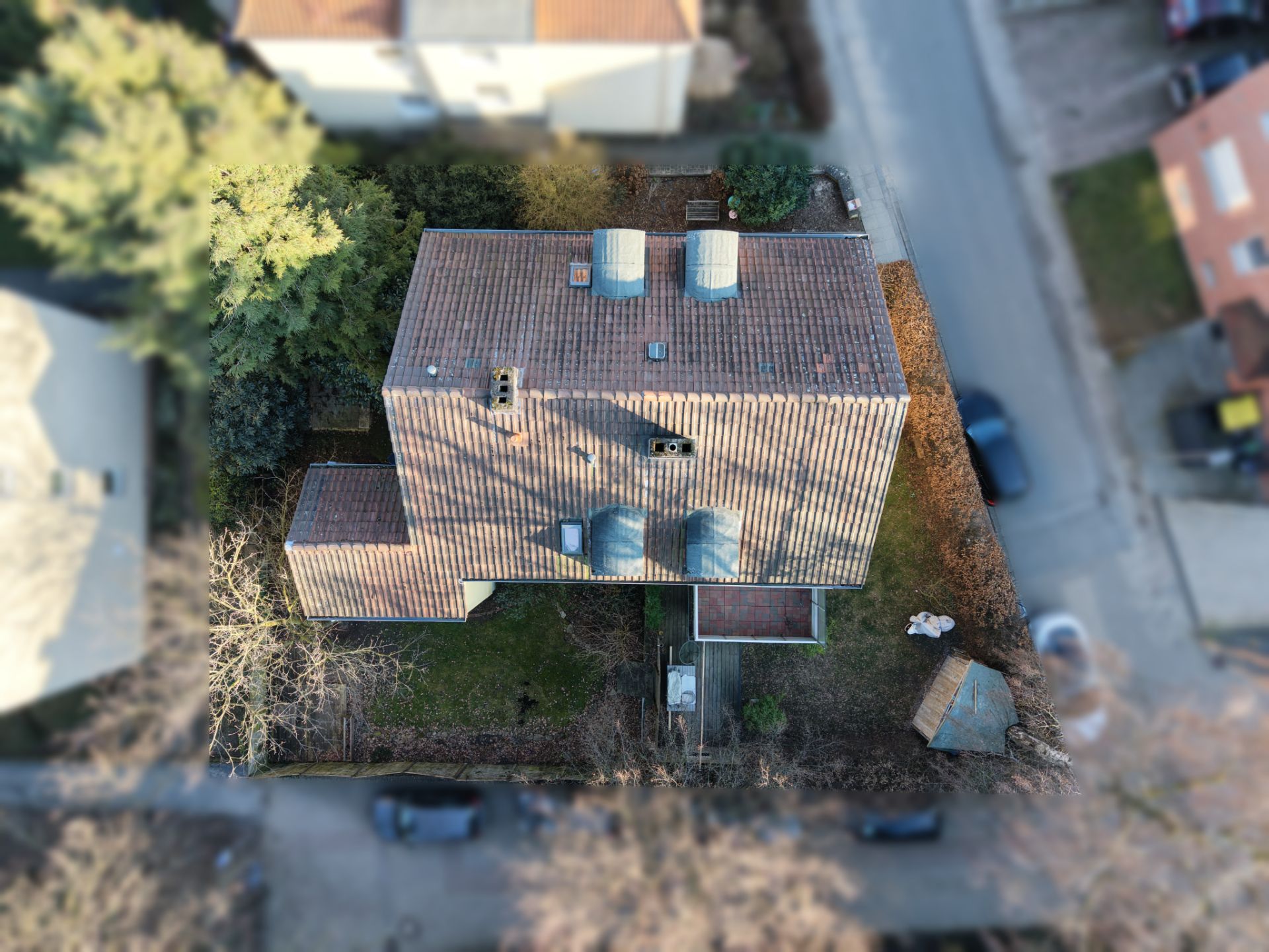 Luftaufnahme eines Einfamilienhauses mit Garten und Terrasse, von oben gesehen.