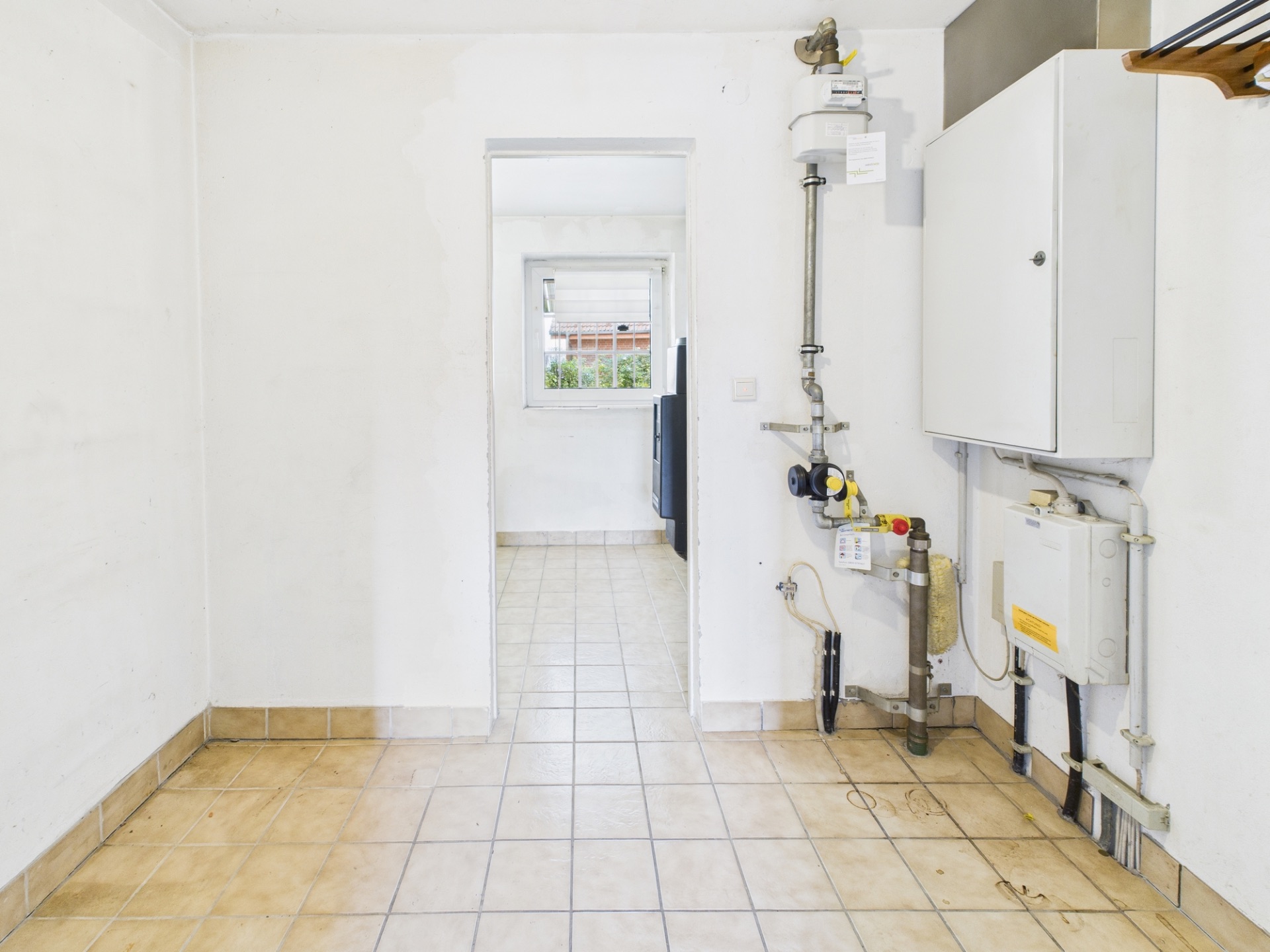 Leerer, gefliester Hauswirtschaftsraum mit Heizungsanlage an der rechten Wand.