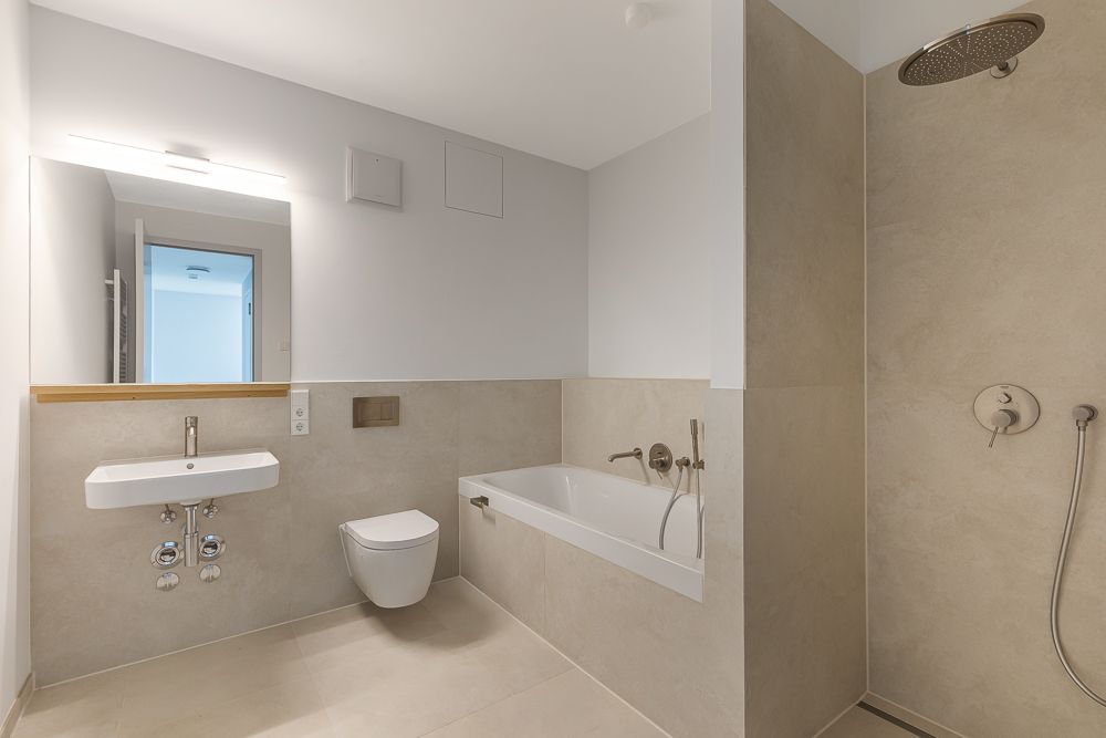 Modernes Badezimmer mit Badewanne, Waschbecken, Toilette und bodengleicher Dusche.