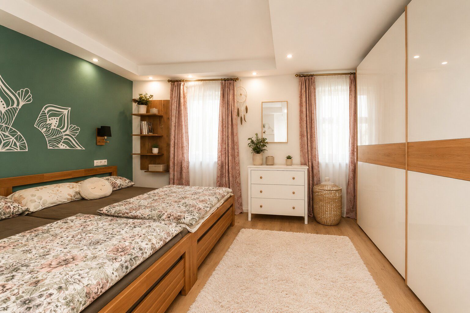 Helles Schlafzimmer mit zwei Betten, großem Schrank, Kommode, Teppich und Wandregal.