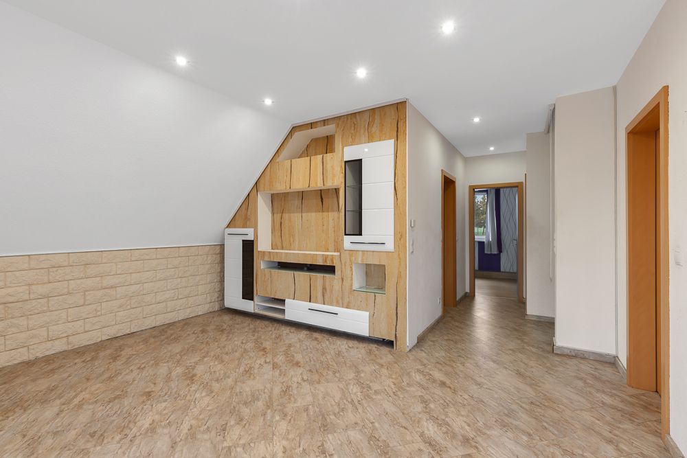 Leerer Wohnraum mit Einbauschrank, Flur und Türen zu weiteren Zimmern.
