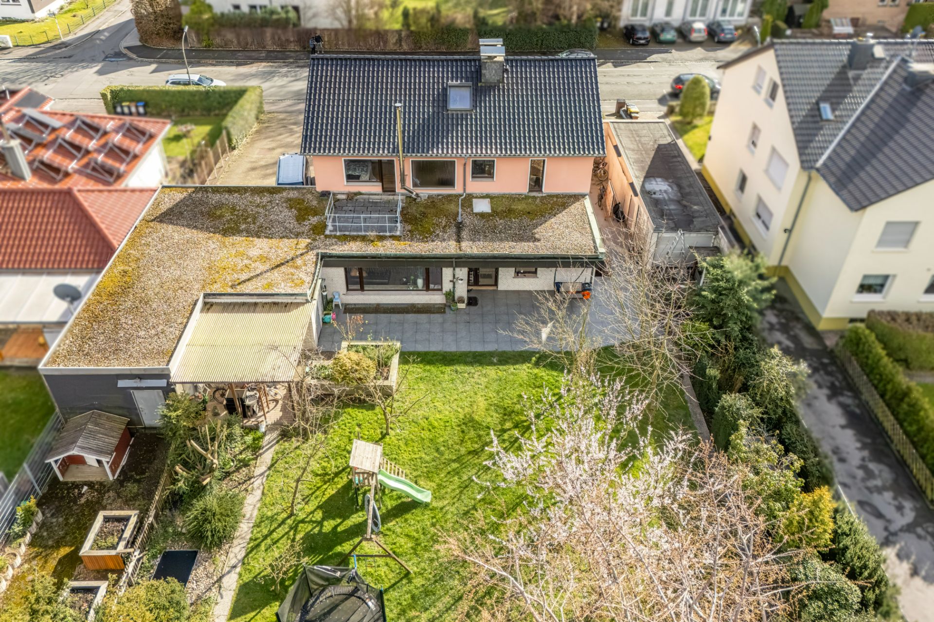 Luftaufnahme eines Wohnhauses mit Garten, Spielplatz und Terrasse.