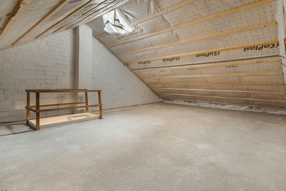 Ausgebauter Dachboden mit schräger Decke, sichtbaren Balken und kleinem Holzgeländer.