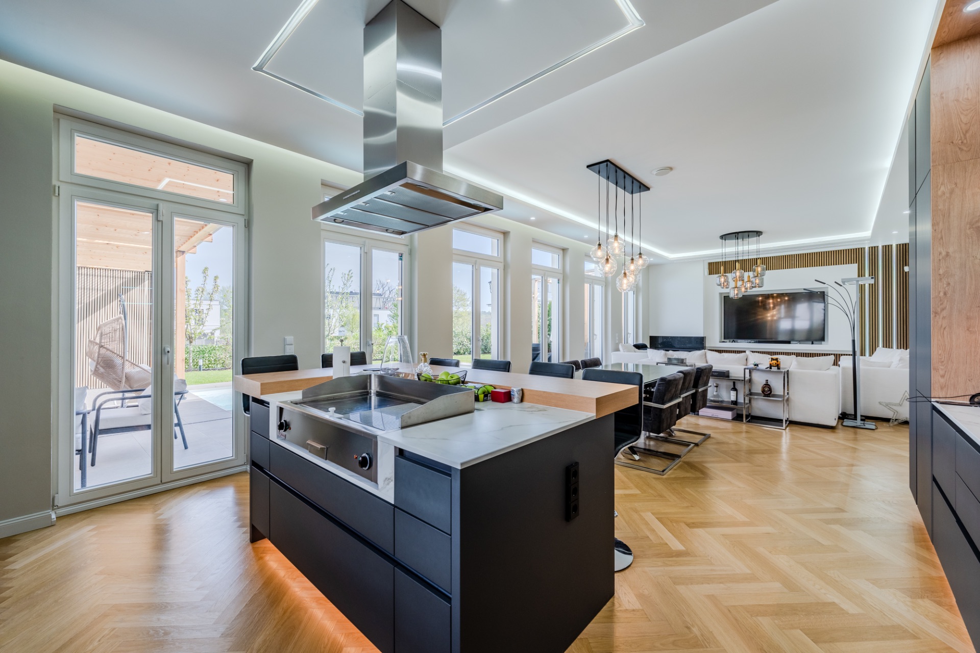 Moderne offene Küche und Wohnzimmer mit großen Fenstern und Holzboden.