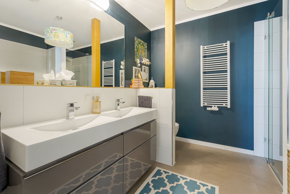 Modernes Badezimmer mit Doppelwaschbecken, dunkler Wand und Handtuchheizkörper.