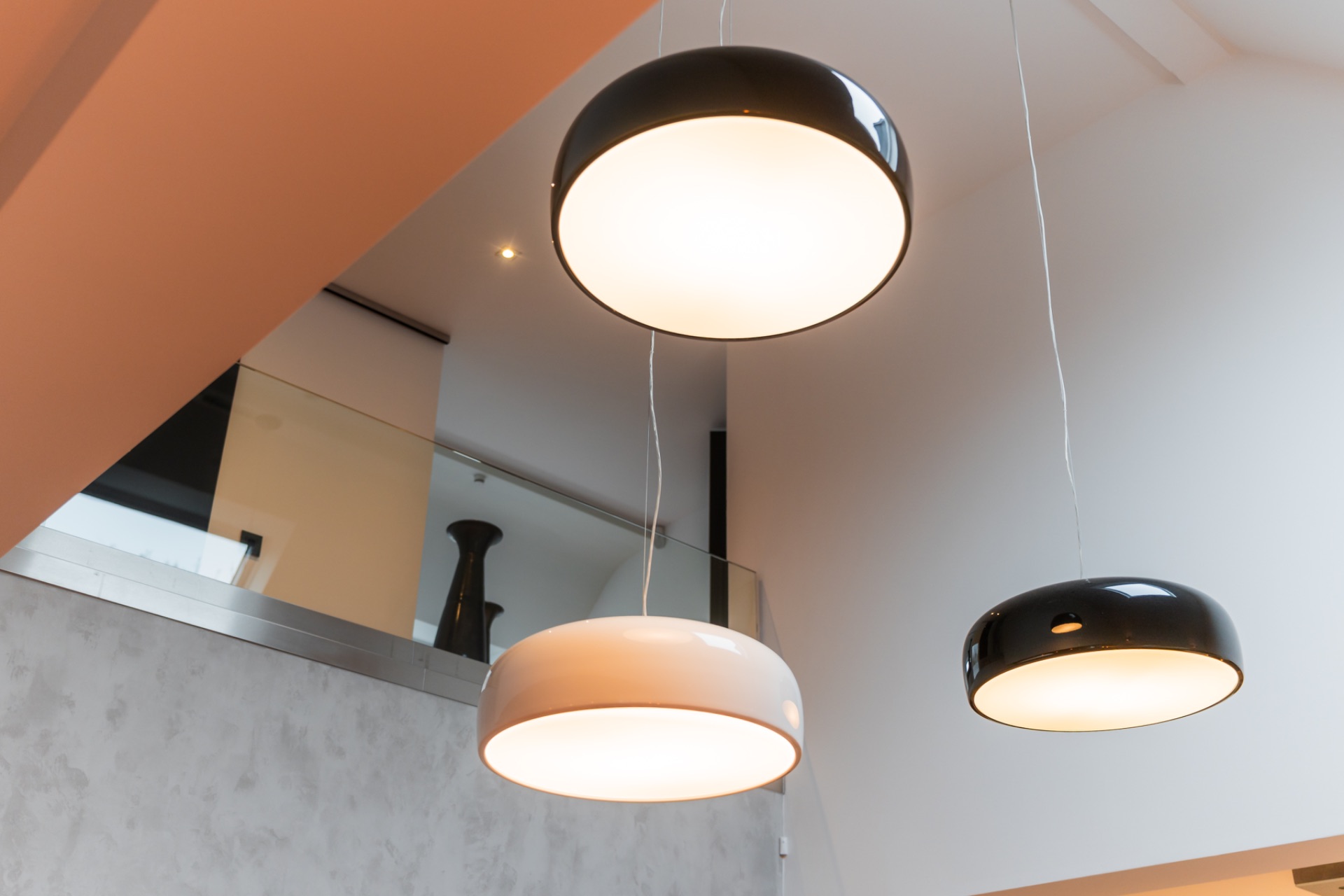 Drei moderne Pendelleuchten hängen von einer weißen Wohnzimmerdecke.