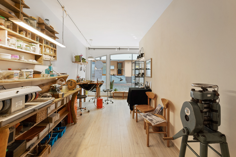 Helles Arbeitszimmer mit Werkbank, Regalen, Werkzeugen und großen Fenstern zum Innenhof.