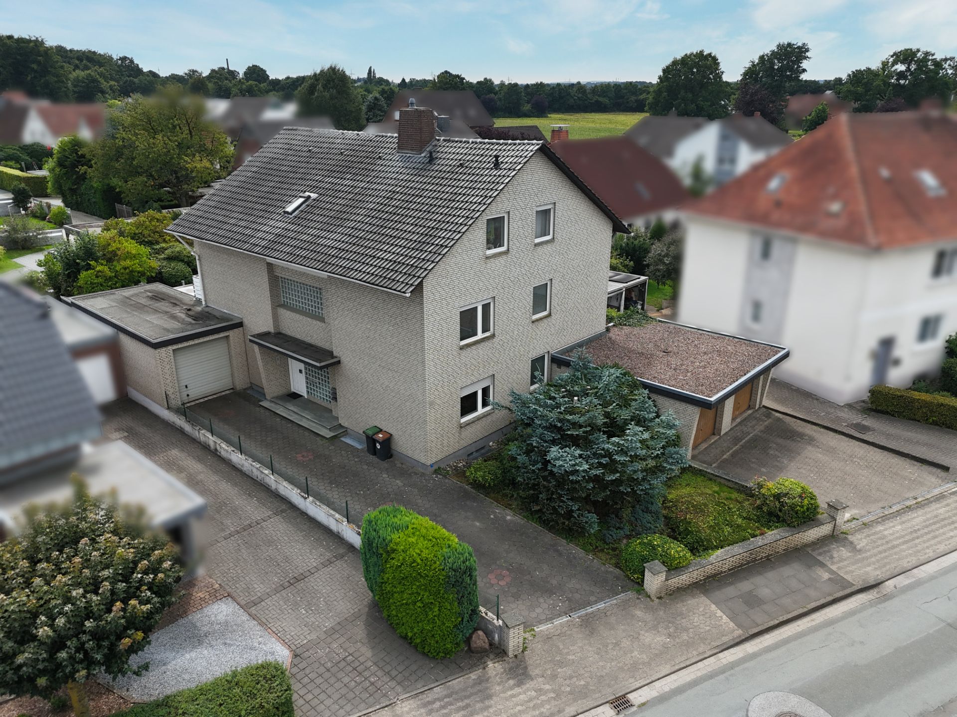 Zweistöckiges Einfamilienhaus mit Garage und Vorgarten an einer Wohnstraße.