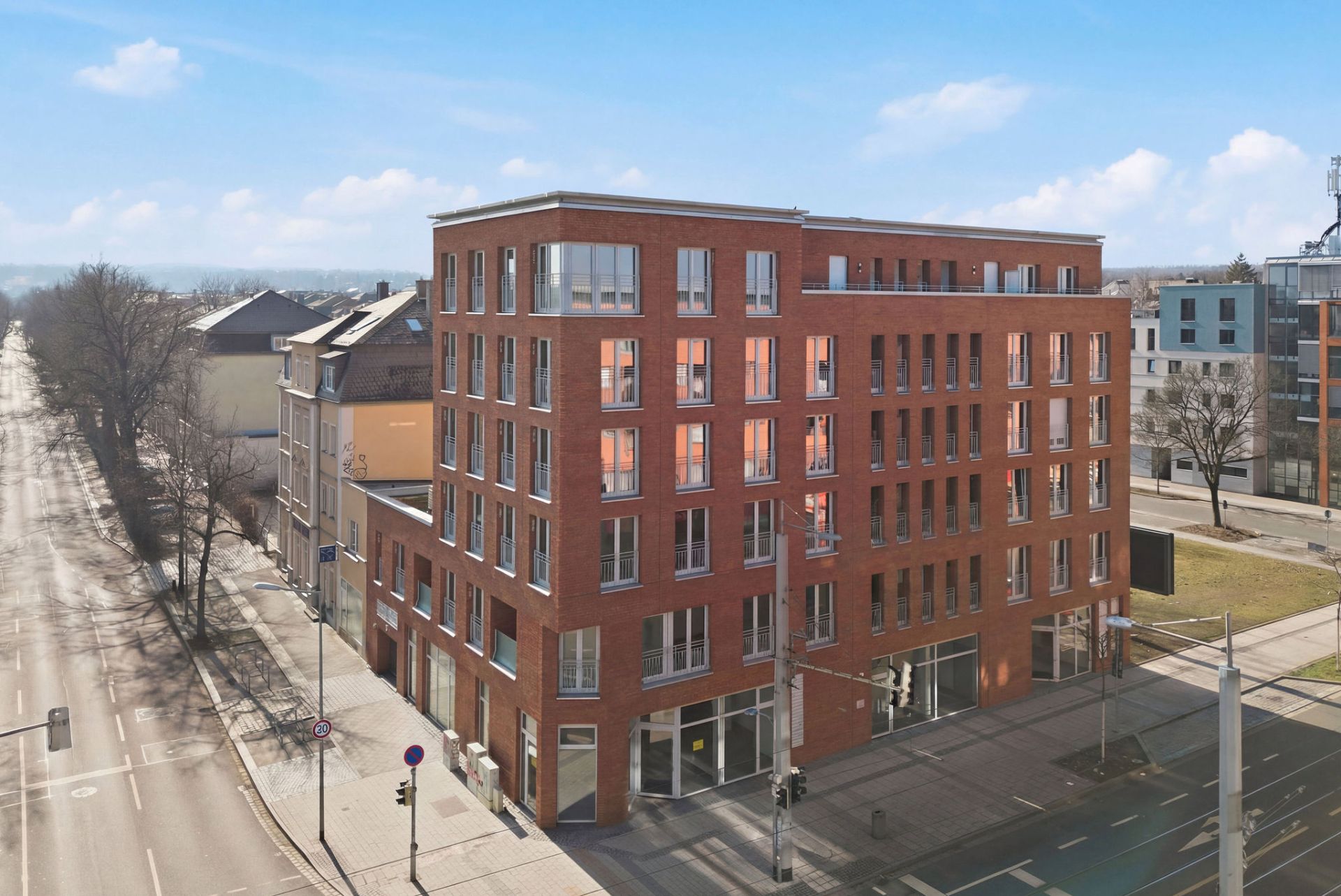 Fünfstöckiges rotes Backsteingebäude an einer Straßenecke mit vielen Fenstern.