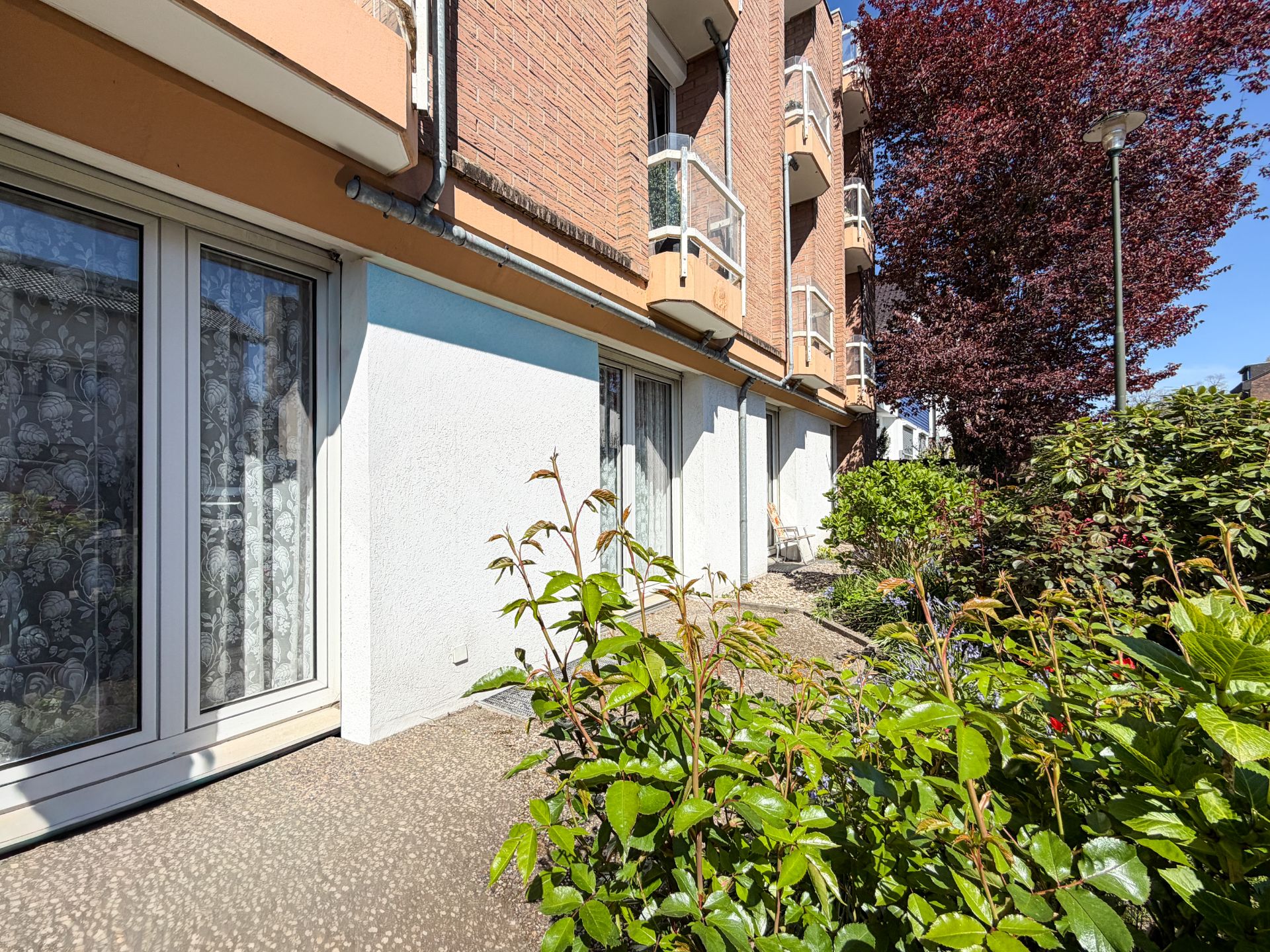 Erdgeschoss eines Mehrfamilienhauses mit Terrasse und umliegenden Pflanzen.