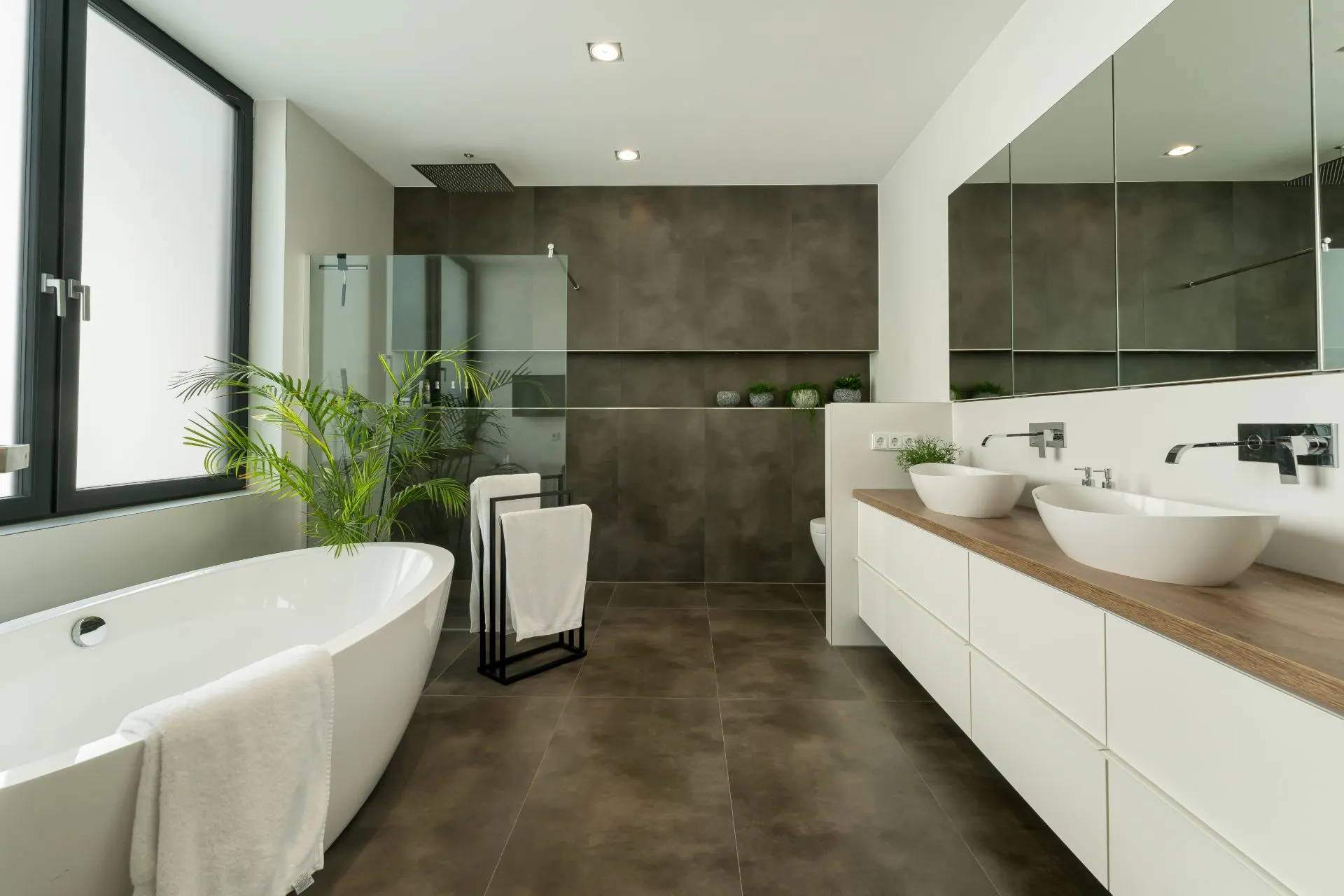 Modernes Badezimmer mit freistehender Badewanne, Doppelwaschbecken und großen Spiegeln.