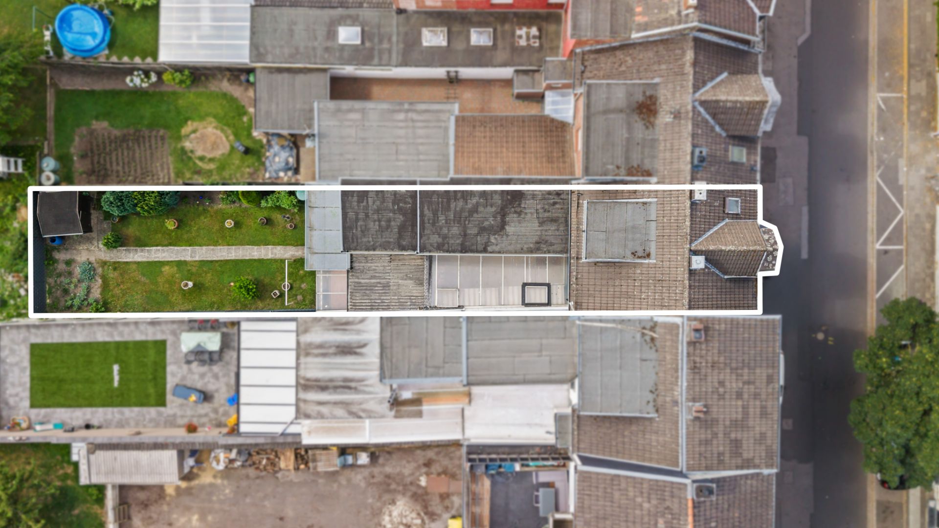 Luftaufnahme eines langen, schmalen Hauses mit Garten, von anderen Häusern umgeben.