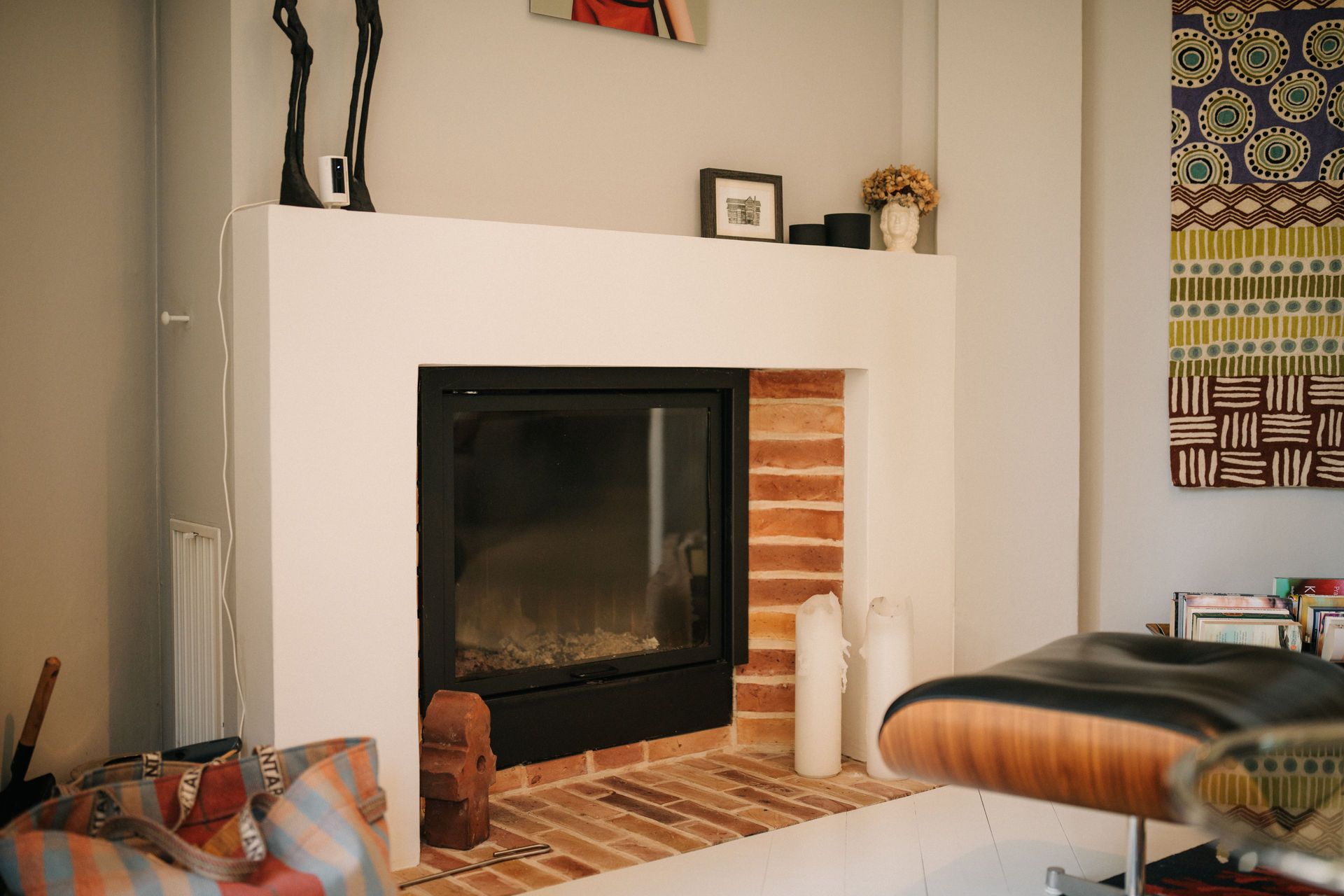 Kamin mit Dekorationen auf dem Sims und Ziegelsteinen auf dem Boden.