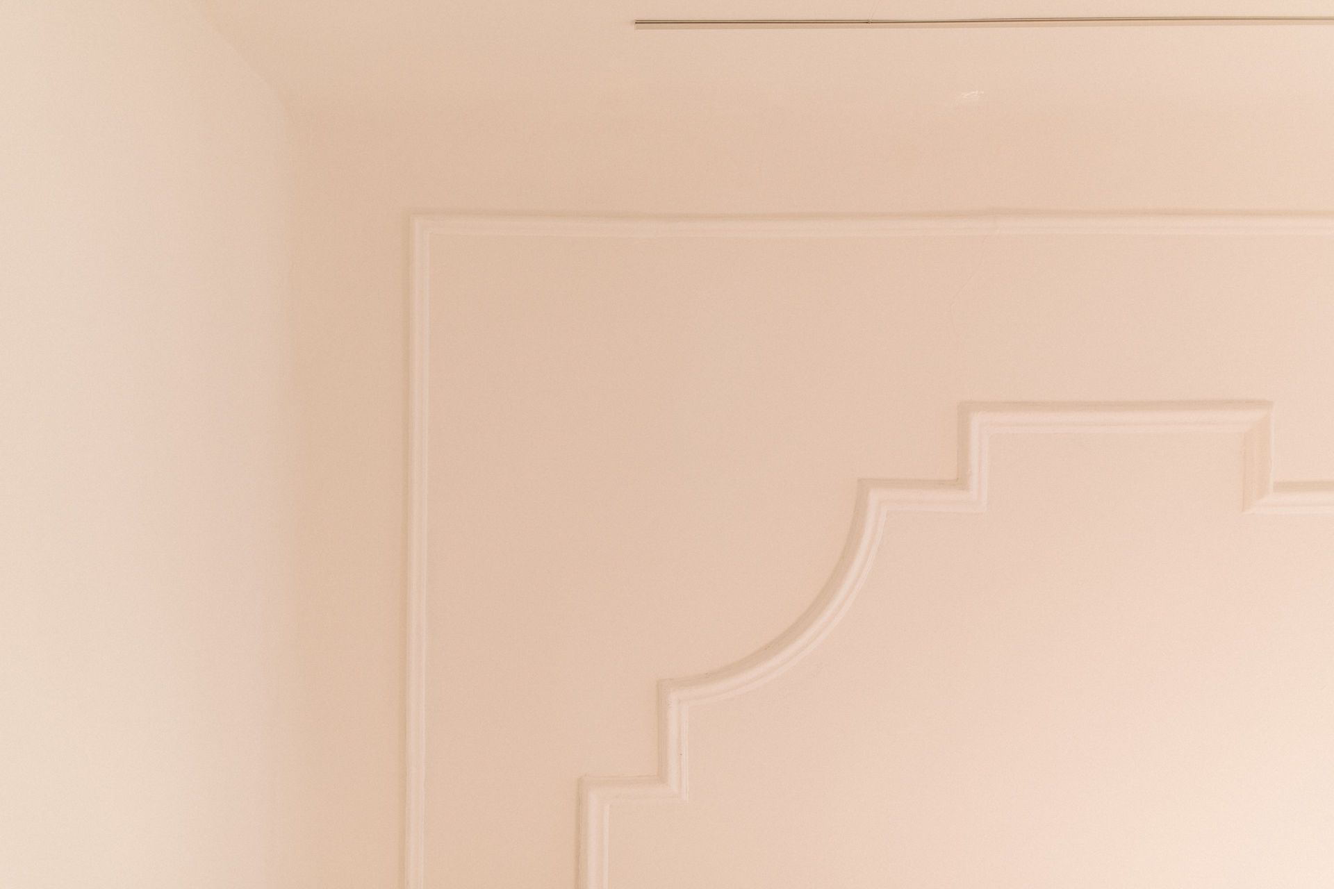 Helle Wand mit dekorativen Stuckelementen und abgerundeten Ecken.