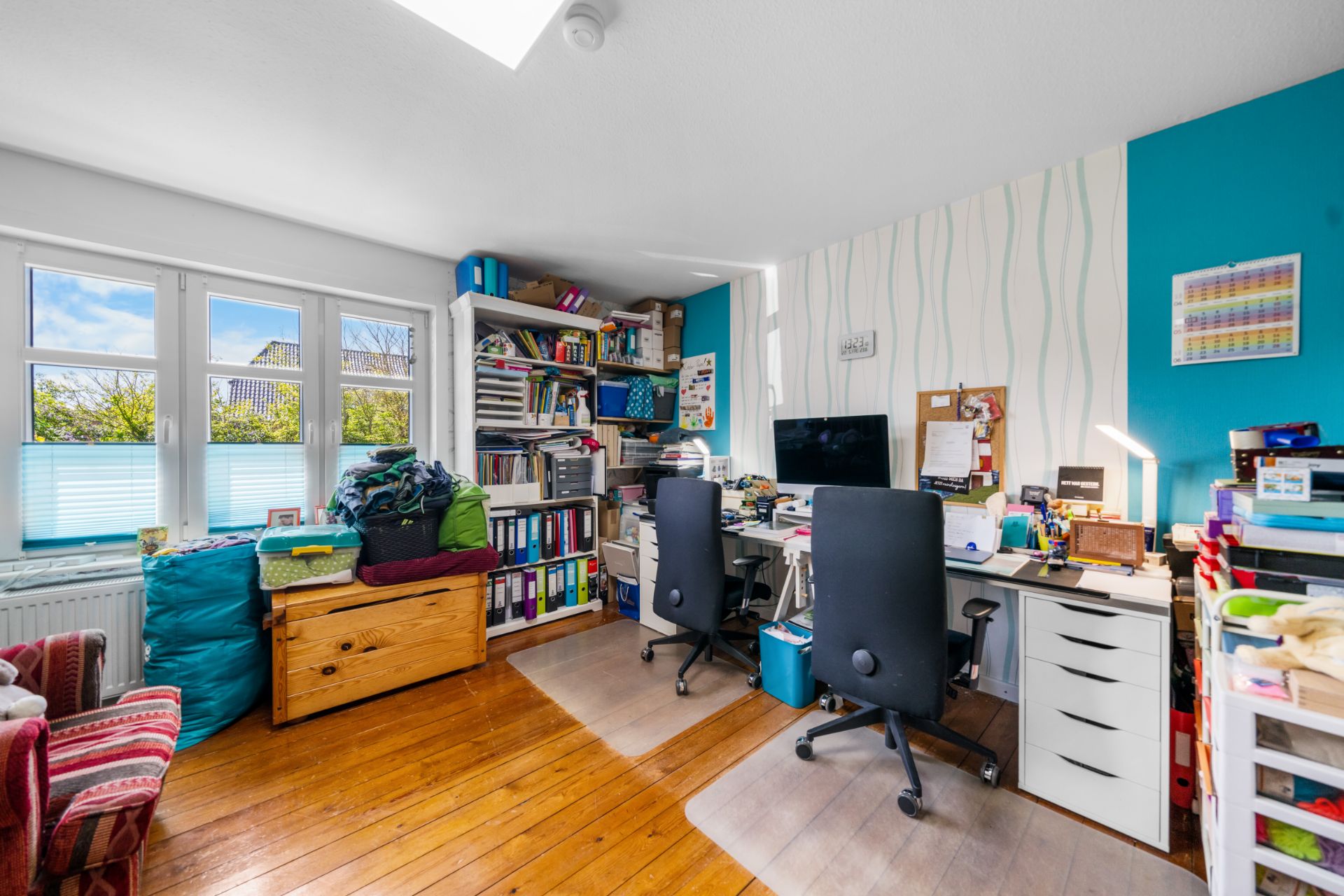 Helles Arbeitszimmer mit zwei Schreibtischen, Regalen voller Bücher und Blick auf den Garten.