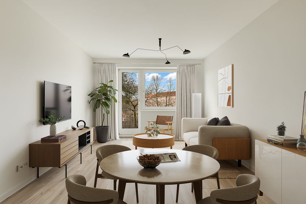 Modernes Wohnzimmer mit Essbereich, Sofa, runder Tisch, Fernseher, Pflanze und großem Fenster.