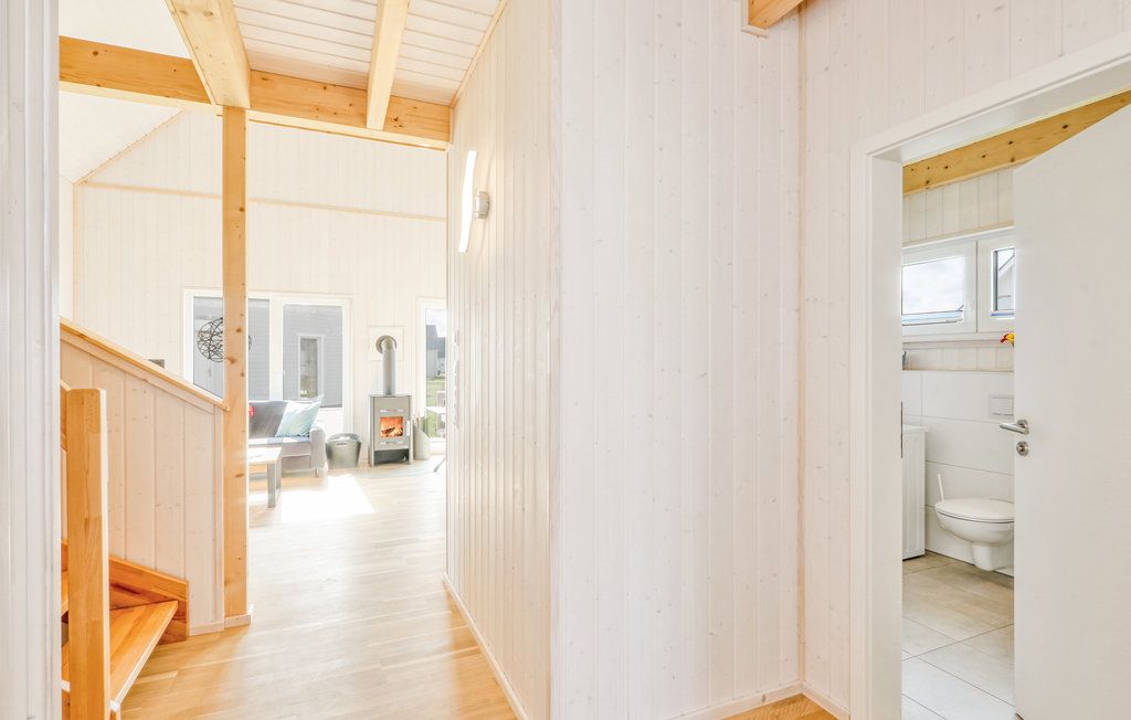 Heller Flur mit Zugang zu Wohnzimmer und Badezimmer, sichtbare Holztreppe und Kamin.