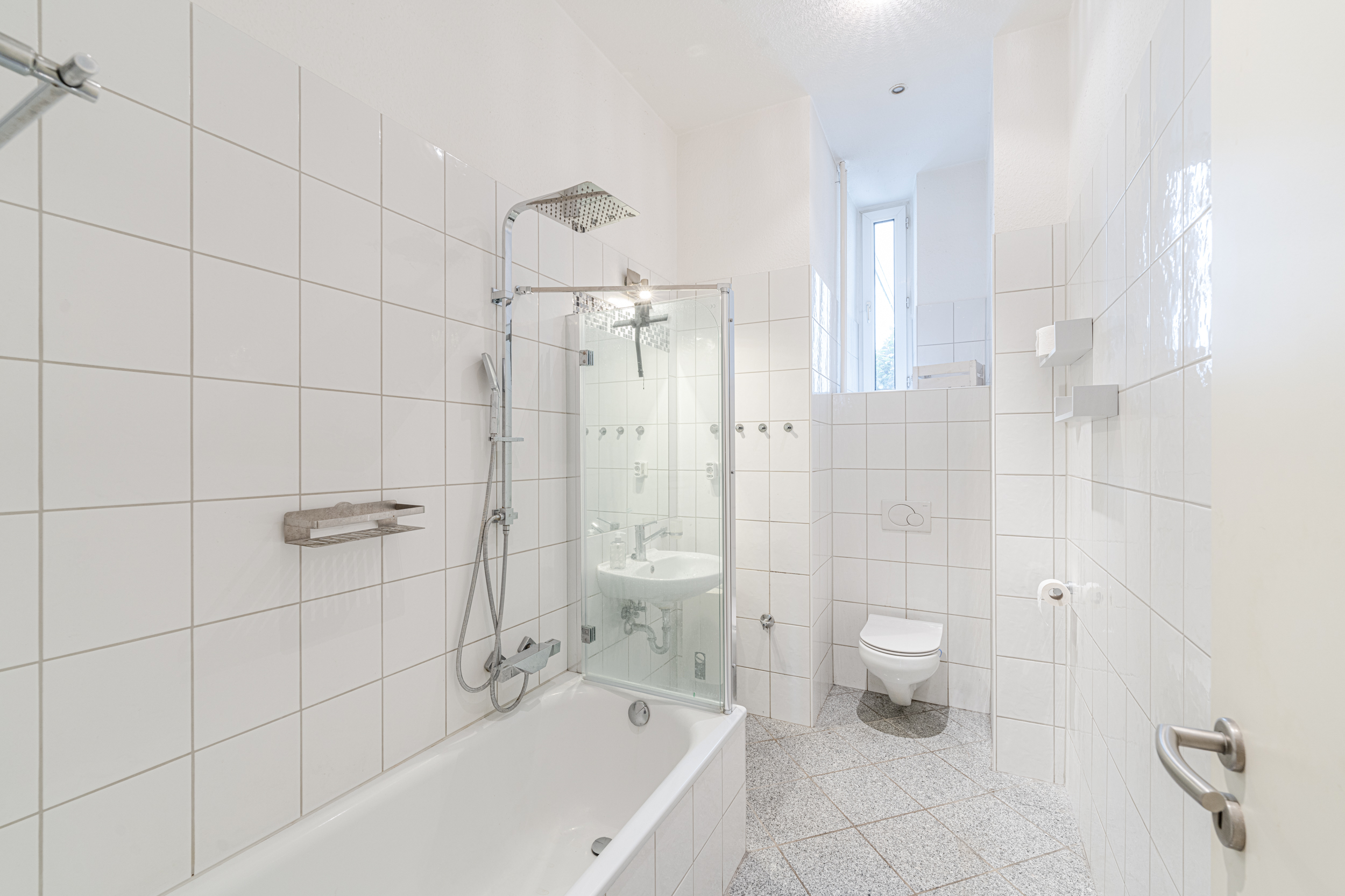 Helles Badezimmer mit Badewanne, Dusche, Waschbecken, Toilette und Fenster.