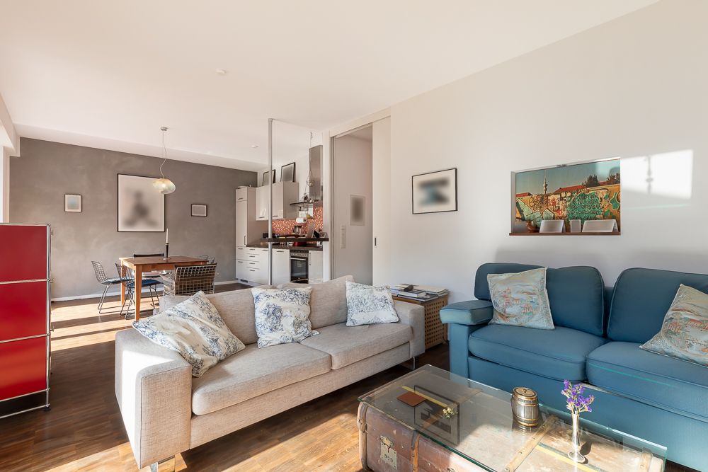Helles Wohnzimmer mit zwei Sofas, Couchtisch und offener Sicht auf Essbereich und Küche.
