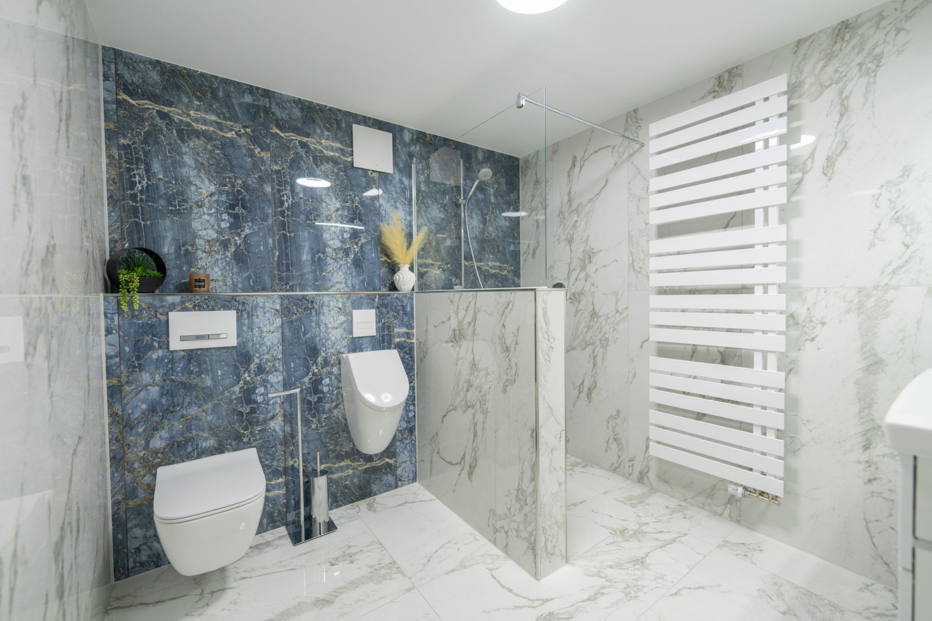 Modernes Bad mit Marmorfliesen, Toilette, Urinal, begehbarer Dusche und Handtuchheizkörper.